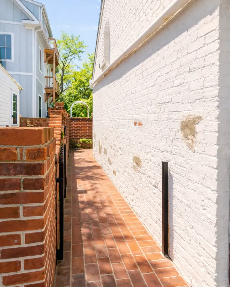 narrow brick walkway along the white brick wall of the building that houses Wildwood Psychotherapy